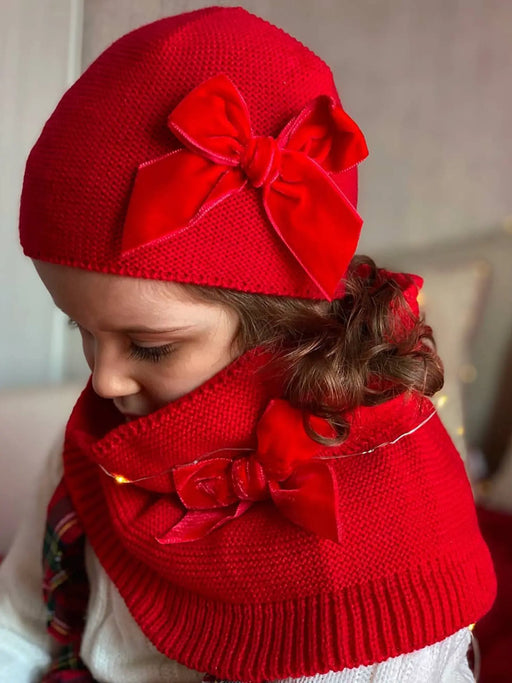 Girl modelling the red Condor knitted had with velvet bow.