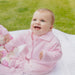 Smiling baby girl wearing the Dandelion pink knitted jacket. 