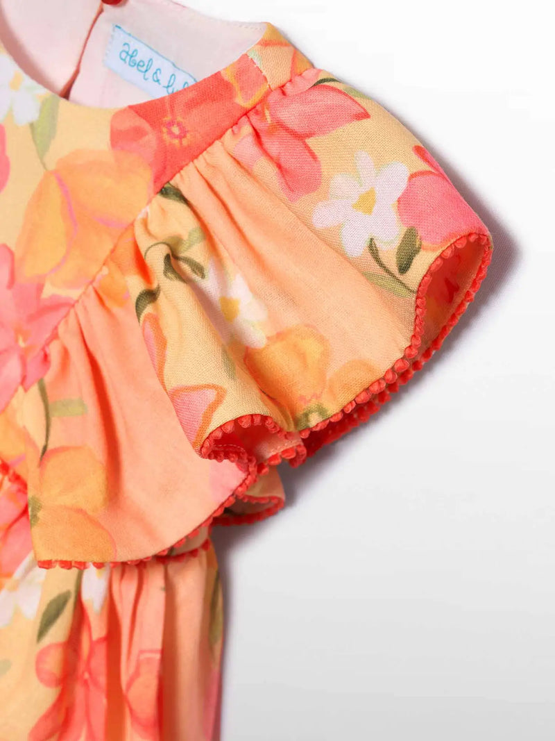 Closer look at the Abel and Lula floral dress showing detail of the red pom pom trim.