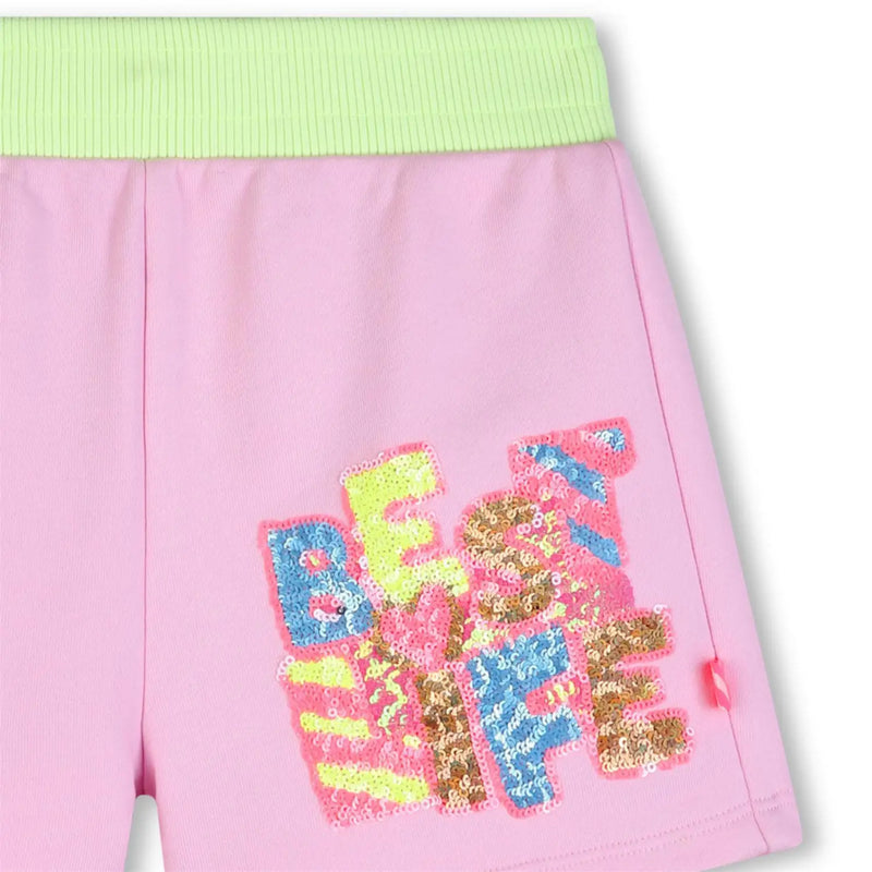 Closer look at the Billieblush track shorts showing detail of the sequin slogan.