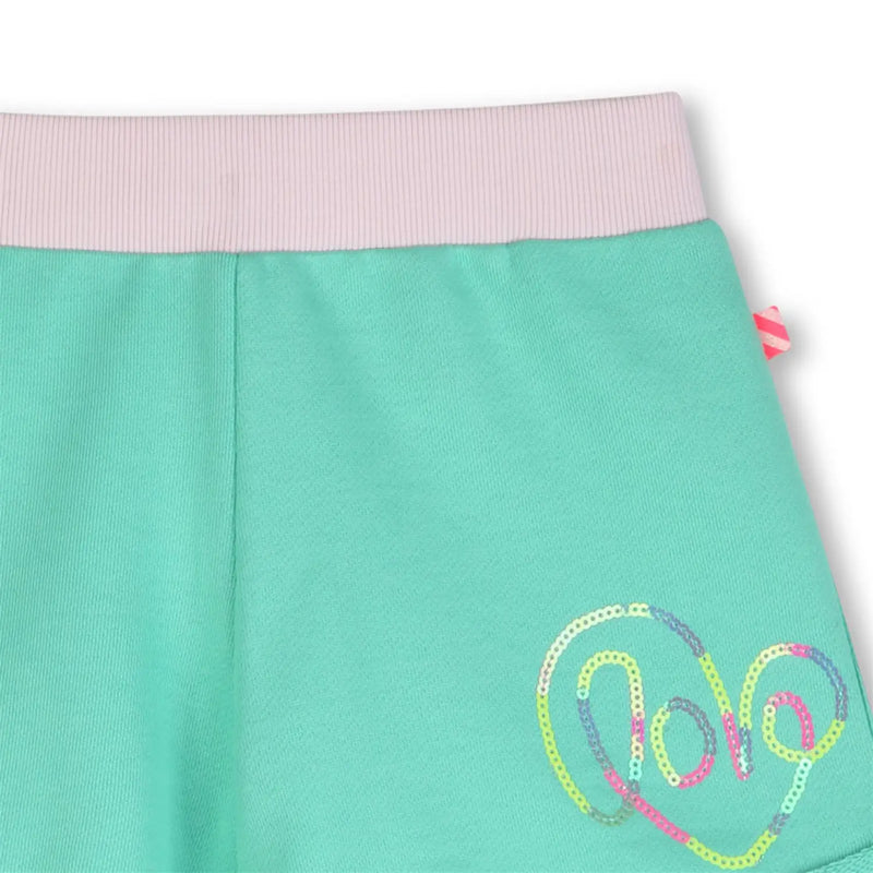 Closer look at the Billieblush track shorts showing detail of the coloured sequin logo.