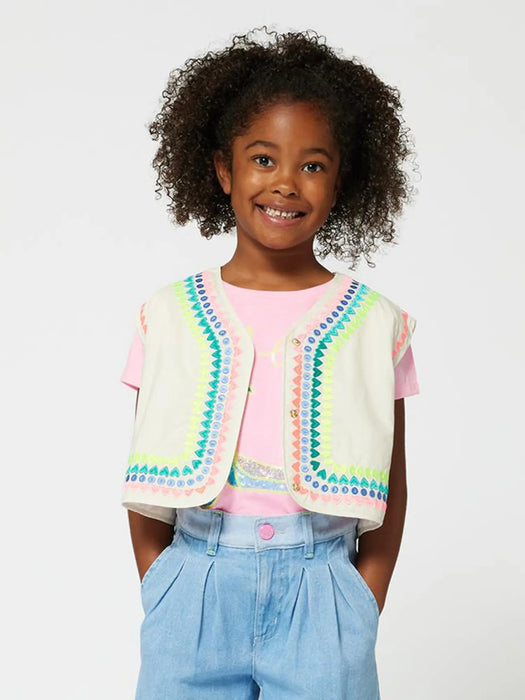 Smiling girl modelling the Billieblush sleeveless jacket.