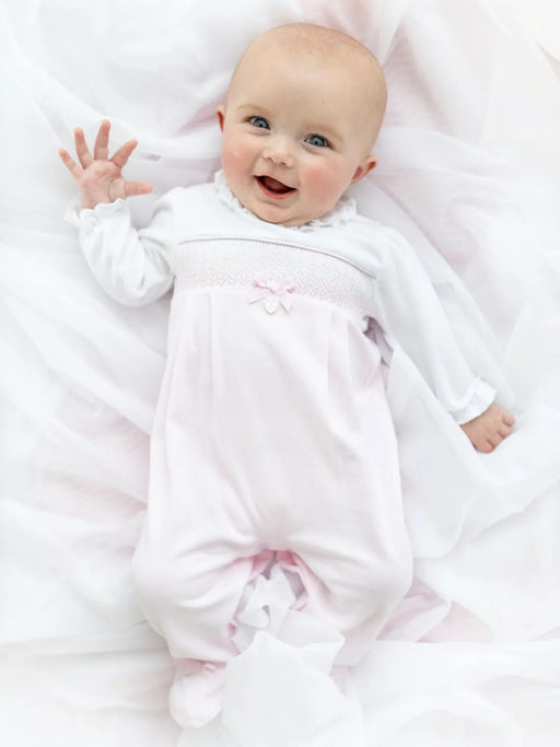 Smiling baby girl modelling the Blues Baby smocked babygrow.