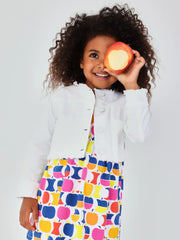 Girl wearing the Boboli denim jacket while holding an apple up up her eye. 