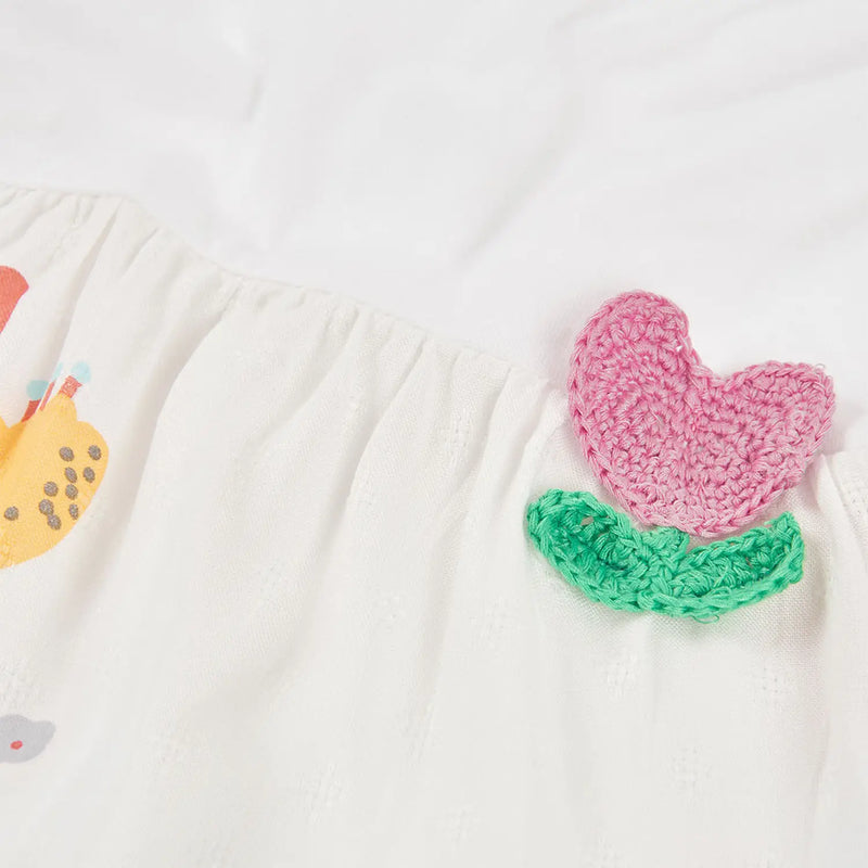 Boboli t-shirt with pink and green crocheted flower at the hip.