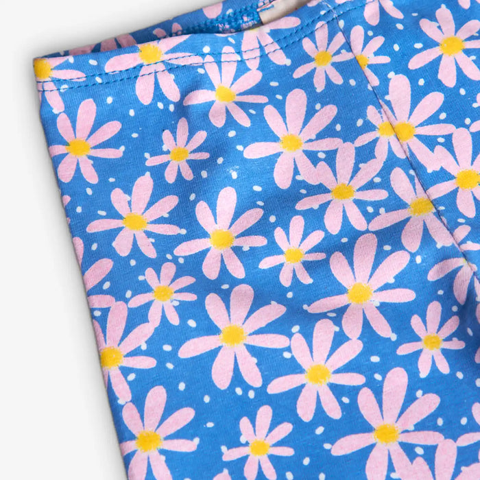 Girl's blue leggings printed with yellow and pink daisies. 