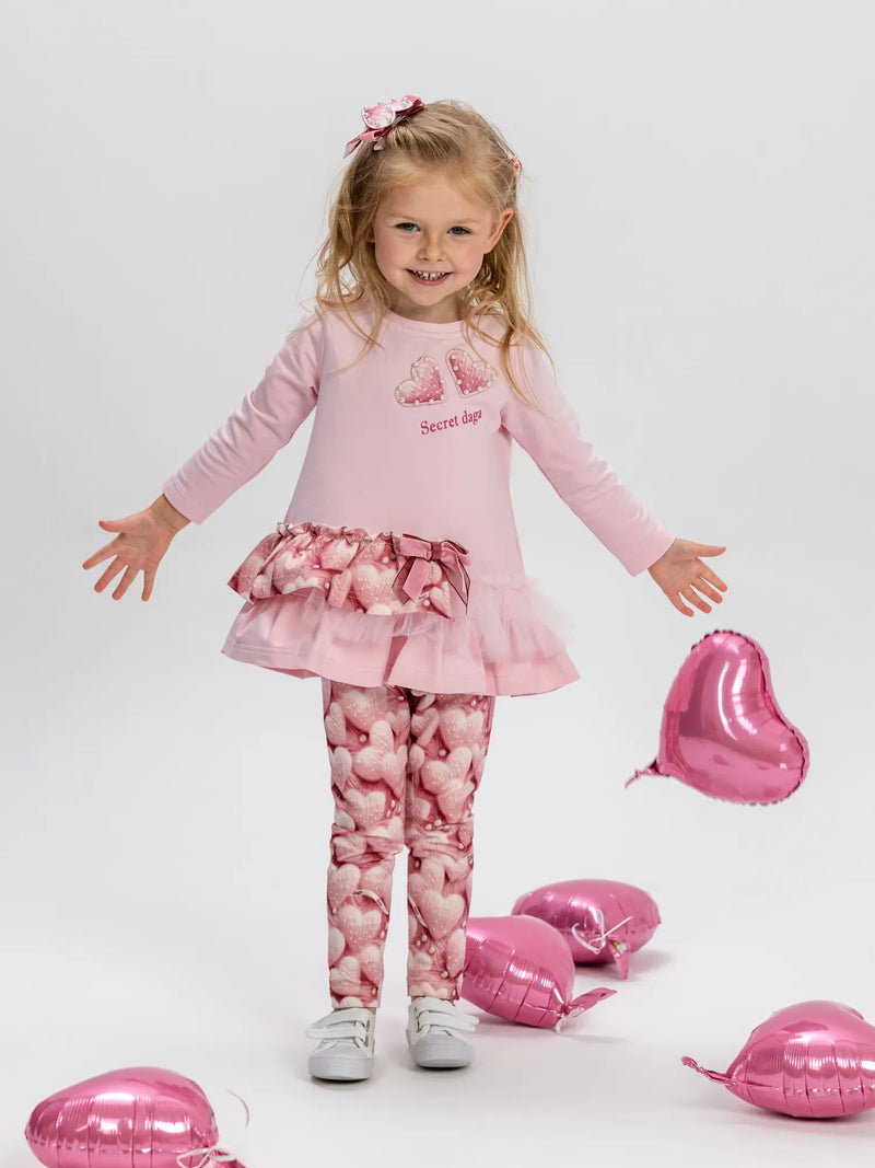 Girl in pink heart print leggings set by Daga.