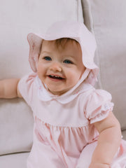 Smiling baby girl modelling the Emile et Rose jade sun hat.