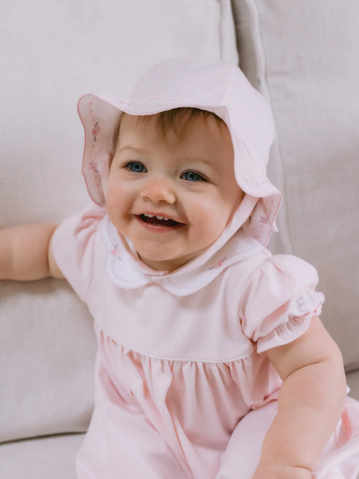 Smiling baby girl modelling the Emile et Rose jade sun hat.