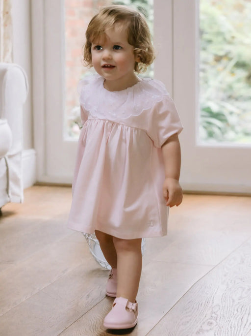 Smiling baby girl modelling the Emile et Rose janais dress.