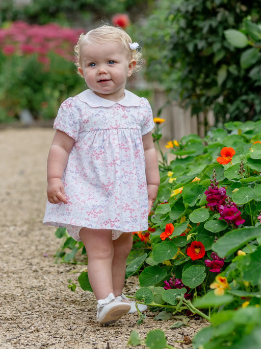 Smiling baby girl modelling the Emile et Rose lola dress.