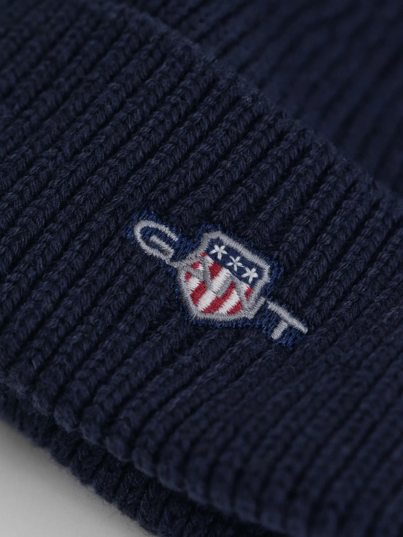 Closer look at the GANT shield beanie showing detail of the embroidered logo.
