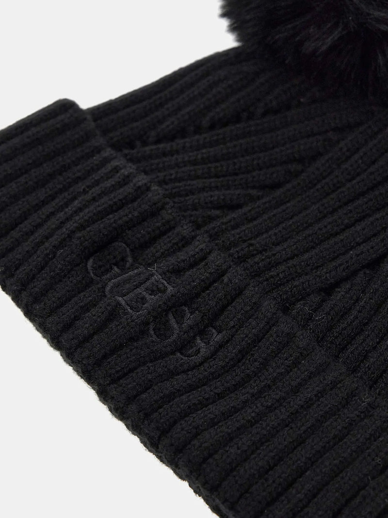 Closer look at the Guess bobble hat showing detail of the embroidered logo.