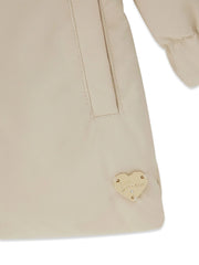 Closer look at the Guess trench coat showing detail of the gold heart badge at the hem.