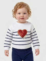 Smiling baby girl modelling the Guess glitter heart tracksuit.