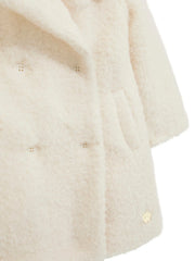 Closer look at the Guess sherpa button coat showing detail of the gold logo badge.