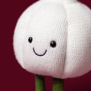 Jellycat amuseables garlic, modelled against a dark purple background.