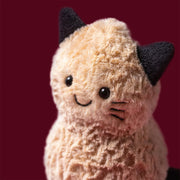 Jellycat amuseables peanut cat, modelled against a dark purple background.