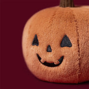 Jellycat ooky jack o lantern, modelled against a dark purple background.