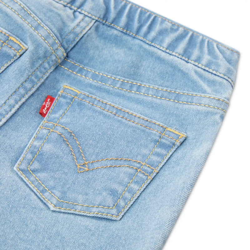 Closer look at the bright blue jeans showing detail of the red logo tag on the back pocket.