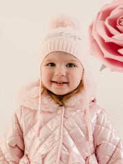 Smiling baby girl modelling the Little A diamond bobble hat.