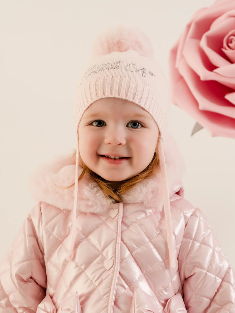 Smiling baby girl modelling the Little A diamond bobble hat.
