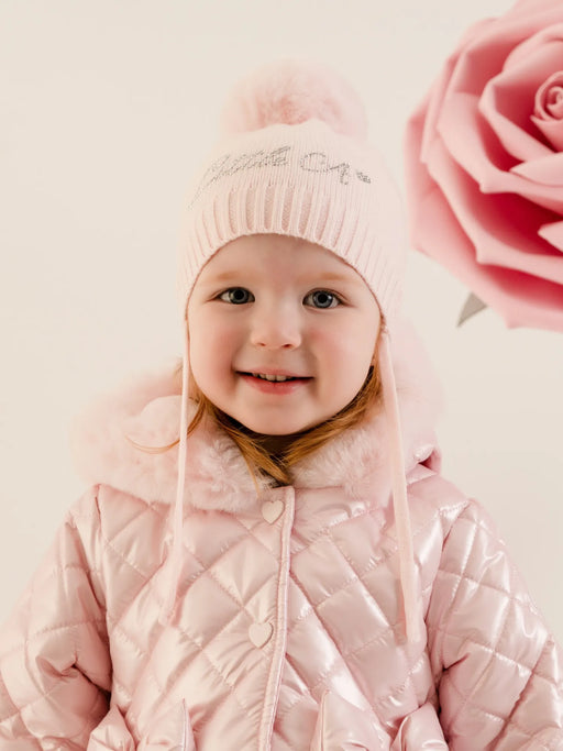 Smiling baby girl modelling the Little A diamond bobble hat.
