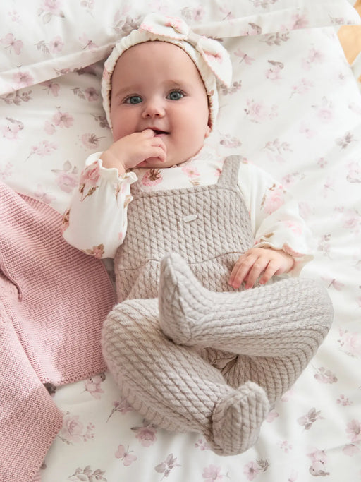 Happy baby girl wearing the beige Mayoral Babygrow & Headband.