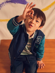 Boy in navy varsity jacket by Mayoral.
