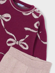 Closer look at the knitted jumper showing detail of the pink bow pattern.