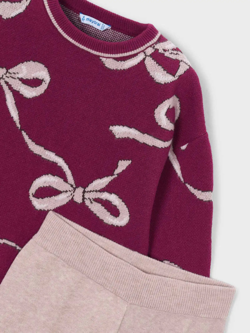 Closer look at the knitted jumper showing detail of the pink bow pattern.