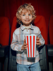 Boy in Mayoral cream checked shirt holding a box of popcorn.