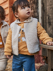 Smiling baby girl modelling the Mayoral faux fur gilet.