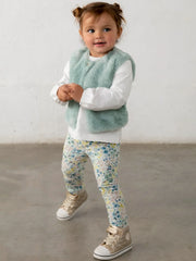 Smiling baby girl modelling the Mayoral faux fur vest & leggings set.