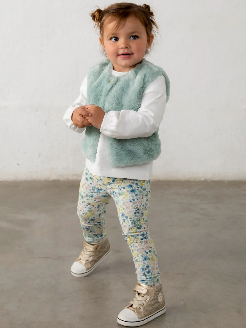 Smiling baby girl modelling the Mayoral faux fur vest & leggings set.