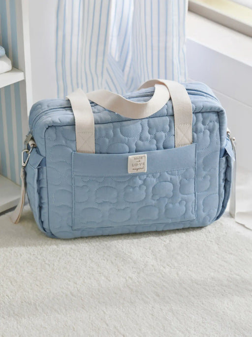 Blue quilted changing bag sitting by a window.