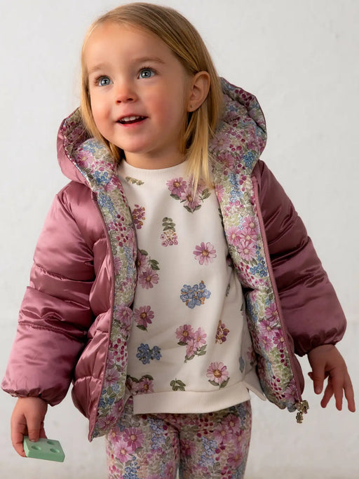 Smiling baby girl modelling the Mayoral reversible coat.
