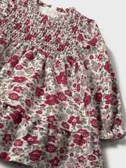 Closer look at the Mayoral smocked dress showing detail of the gold logo badge on the chest.