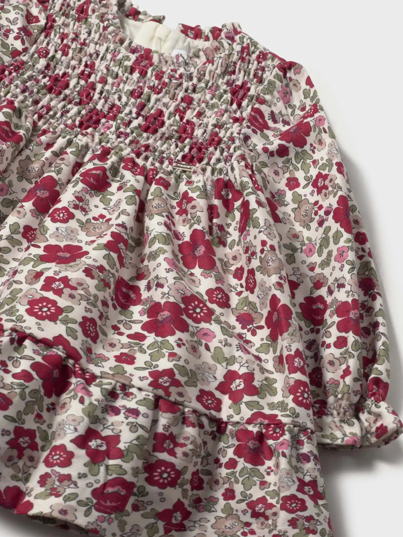 Closer look at the Mayoral smocked dress showing detail of the gold logo badge on the chest.