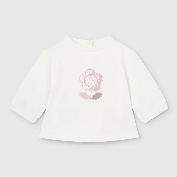 Newborn girl's white top with flower appliqué on the chest.