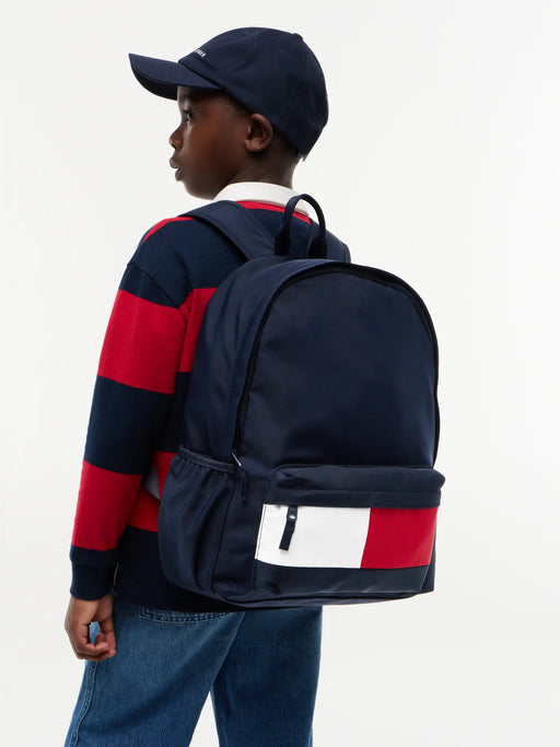 boy modelling the Tommy Hilfiger flag backpack.
