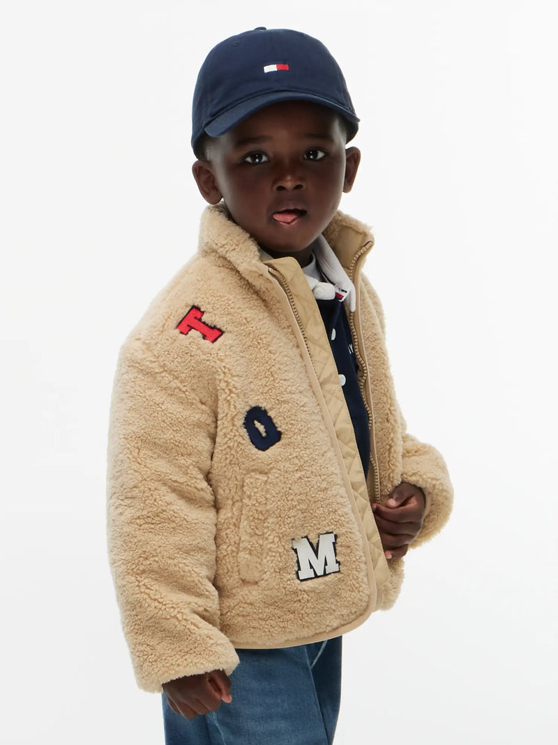 Closer look at the Tommy Hilfiger fleece jacket showing detail of the embroidered letter patches.