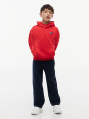 Boy in red heritage flag hoodie by Tommy Hilfiger.