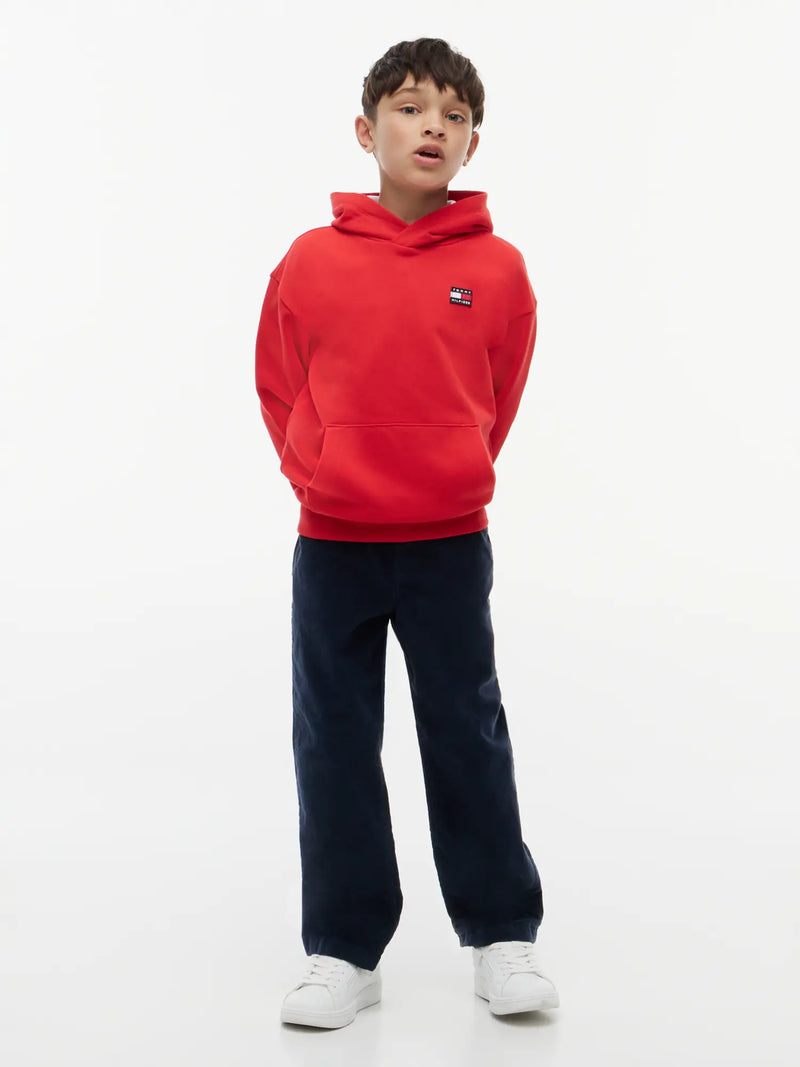 Boy in red heritage flag hoodie by Tommy Hilfiger.