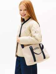 Smiling girl modelling the Tommy Hilfiger monotype bag.