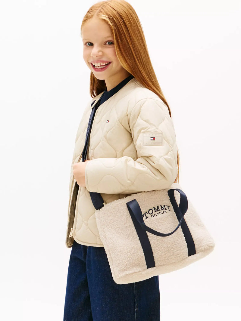 Smiling girl modelling the Tommy Hilfiger monotype bag.