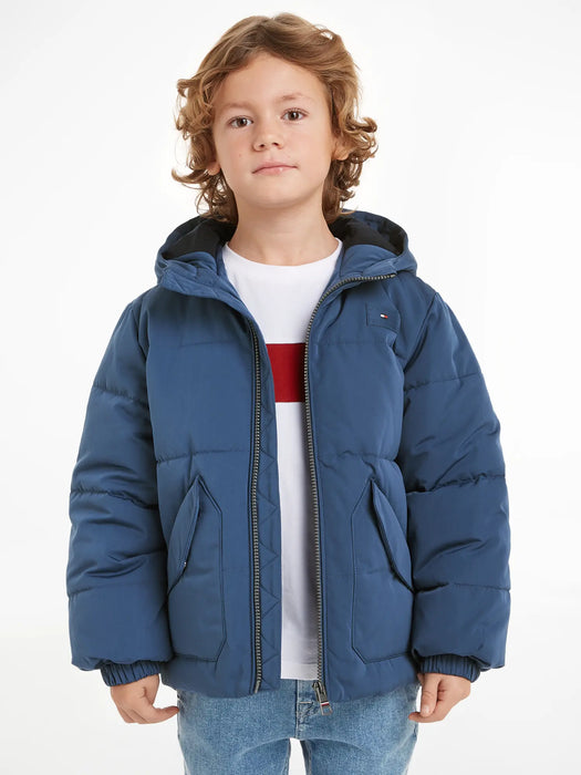 Boy wearing the Tommy Hilfiger monotype puffer jacket.