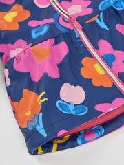 Closer look at the Tuc Tuc printed raincoat showing detail of the glitter logo patch at the hem.