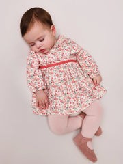 Sleeping baby girl in orange patio dress by Tutto Piccolo.