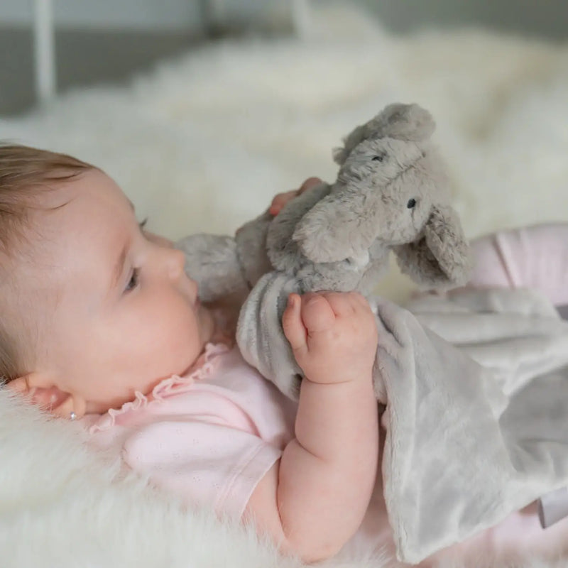 Baby girl clutching the Ziggle elephant comforter.